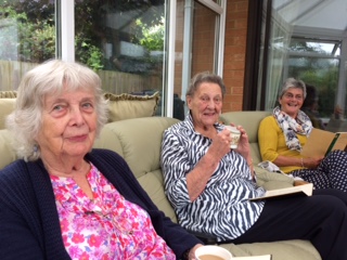 Three women smiling at the camera with books open on their laps