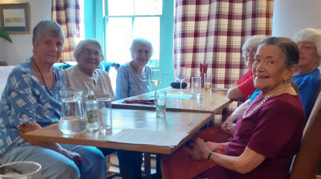 6 smiling women at a table
