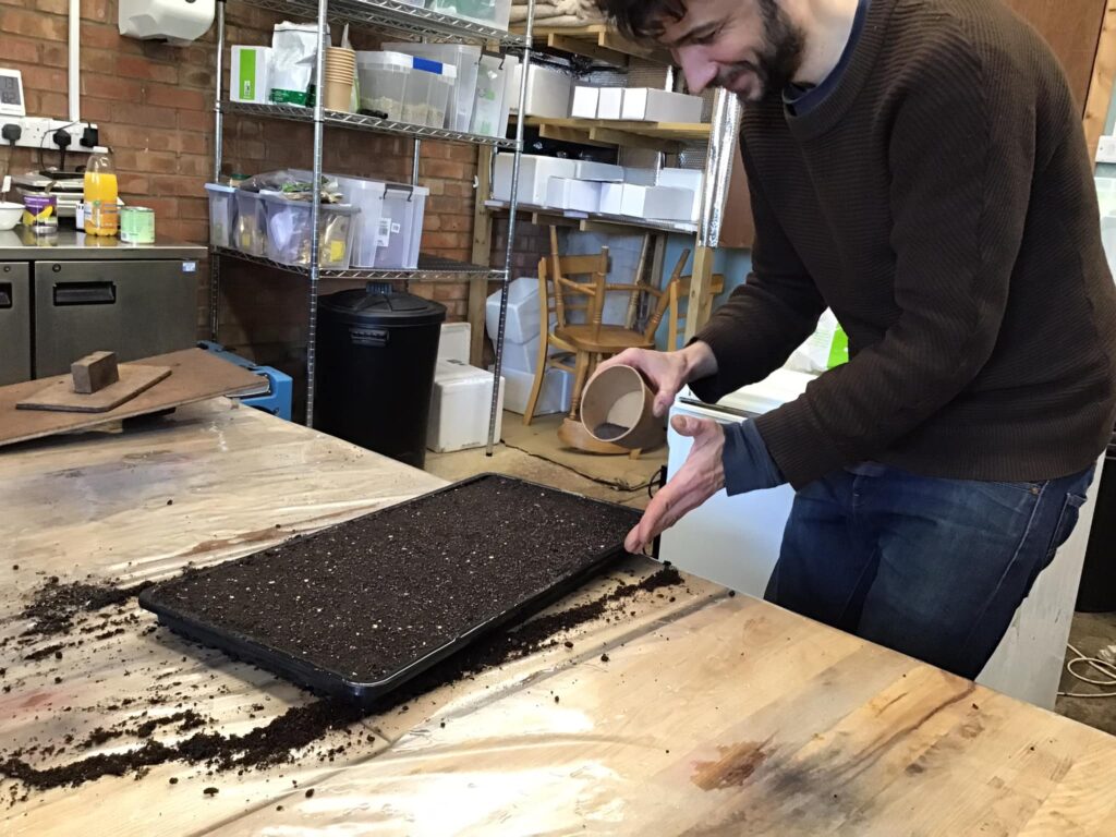 A man filling a tray with compost
