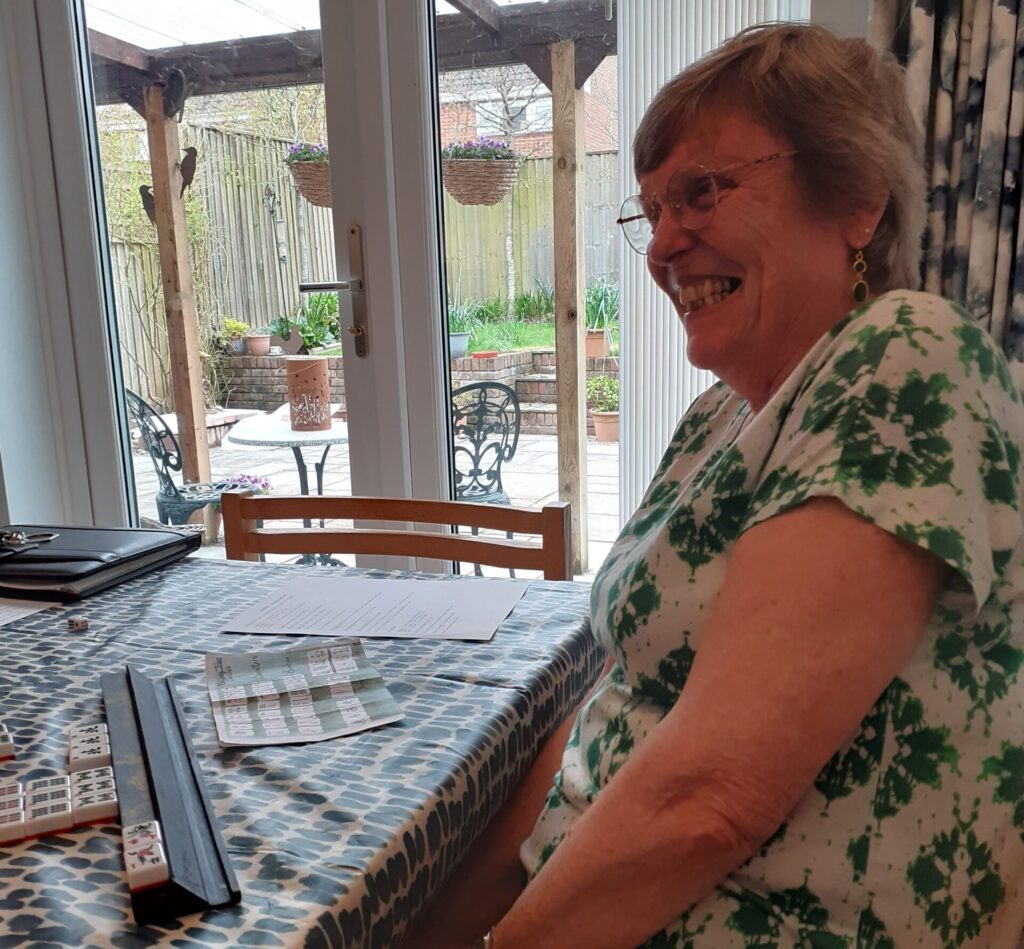 A woman smiling by a Mah Jong game