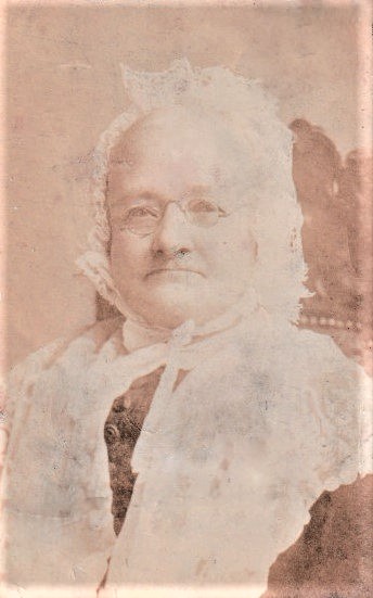 Sepia photo of an old lady in a white lace bonnet and shawl
