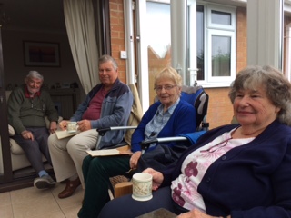 Two men and two women with open books, one with a mug