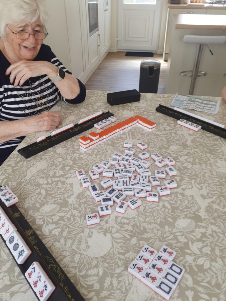 A Mah Jong game in progress with a woman smiling.